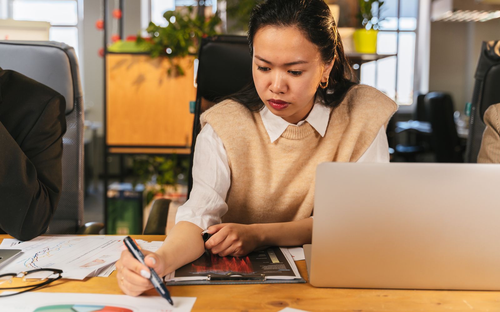 A professional using a laptop and reviewing business charts
